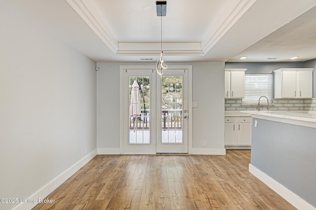 9003 Holly Village Ct, Lyndon, KY 40242 - unfurnished dining area with baseboards, a healthy amount of sunlight, a tray ceiling, and light wood finished floors