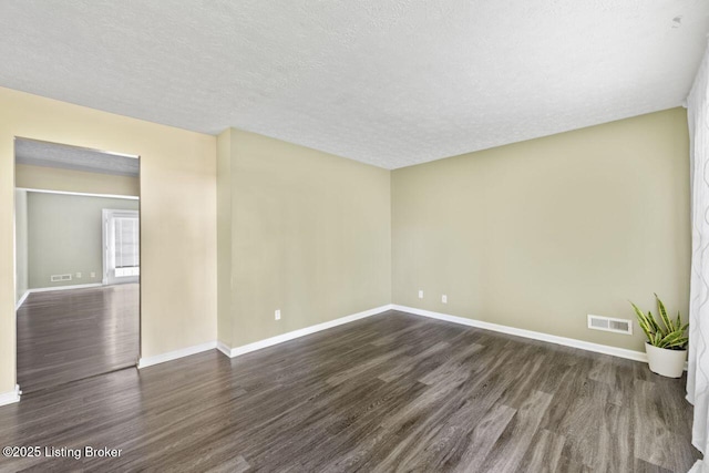 unfurnished room featuring a textured ceiling, visible vents, baseboards, and dark wood-type flooring