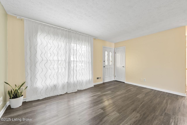 spare room with baseboards, a textured ceiling, and dark wood-style flooring