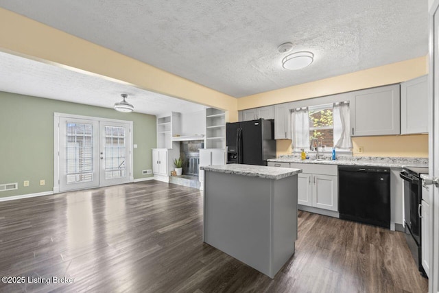 kitchen with black appliances, open floor plan, dark wood-style flooring, and a sink