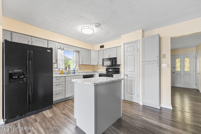 kitchen featuring gray cabinetry, black appliances, dark wood-style flooring, and a sink
