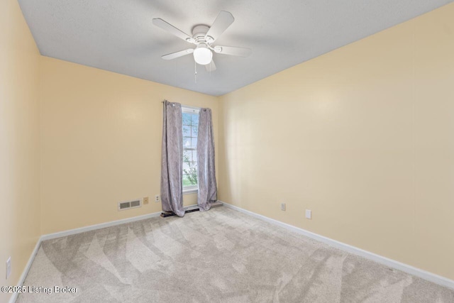 carpeted spare room with visible vents, a ceiling fan, and baseboards