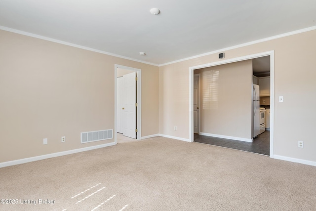 carpeted spare room featuring baseboards, visible vents, and crown molding
