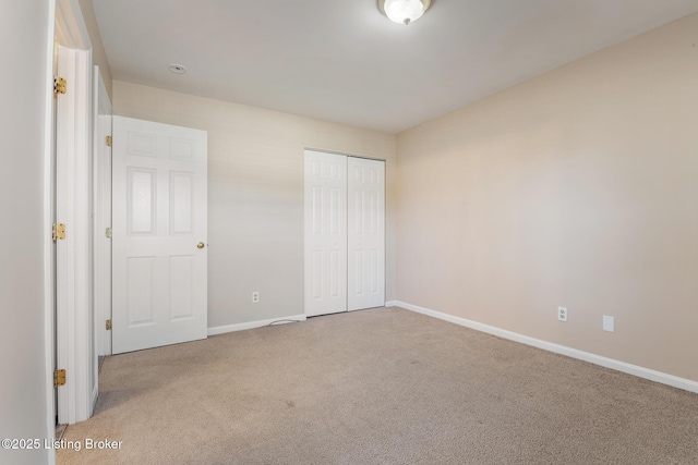 unfurnished bedroom featuring baseboards, carpet flooring, and a closet