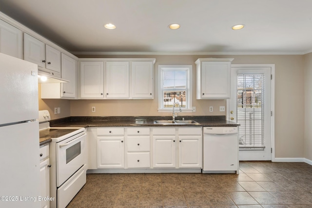 kitchen with dark countertops, crown molding, a sink, white appliances, and under cabinet range hood