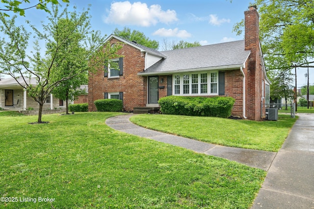 tri-level home with a chimney, central AC, a front yard, and brick siding