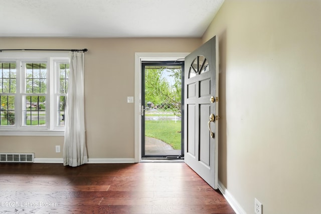 foyer entrance featuring visible vents, wood finished floors, and a healthy amount of sunlight