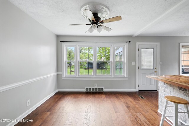 interior space with dark wood-style flooring, visible vents, and ceiling fan