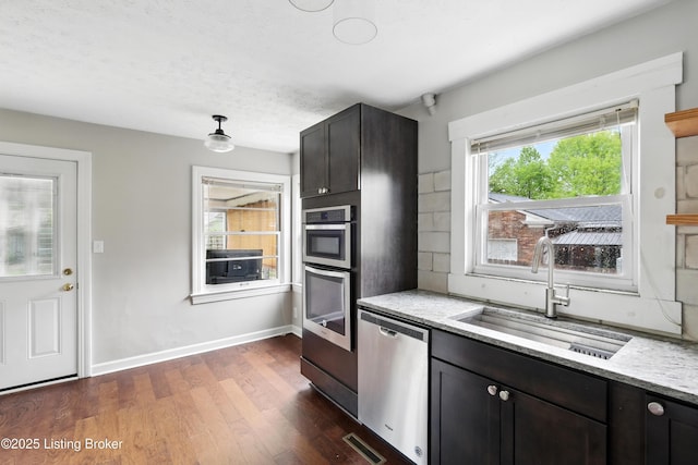 kitchen with dark wood finished floors, appliances with stainless steel finishes, a sink, baseboards, and visible vents