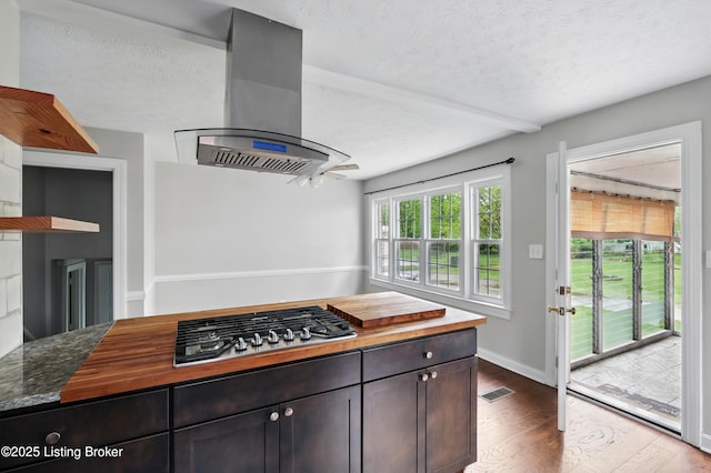 kitchen with a textured ceiling, visible vents, dark wood-style floors, island exhaust hood, and stainless steel gas cooktop