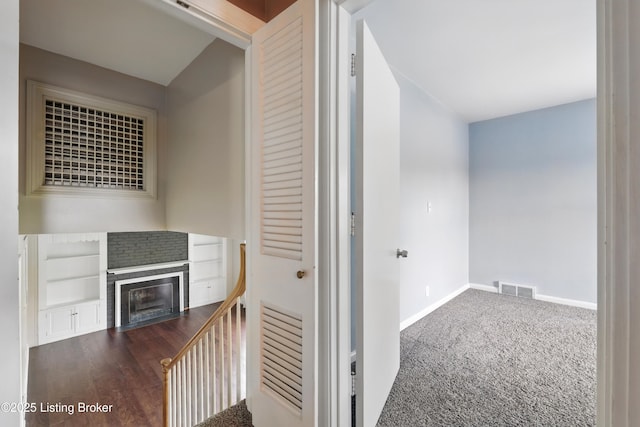 hall with built in shelves, an upstairs landing, visible vents, and baseboards