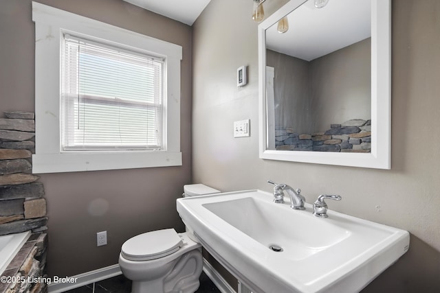 bathroom featuring toilet, baseboards, and a sink