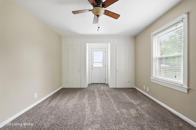 carpeted spare room with ceiling fan and baseboards