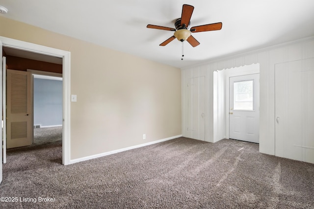 carpeted spare room featuring baseboards and a ceiling fan