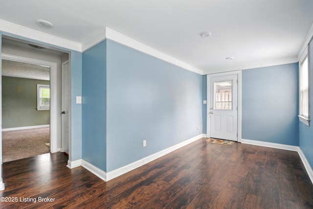 unfurnished room with wood finished floors, crown molding, visible vents, and baseboards