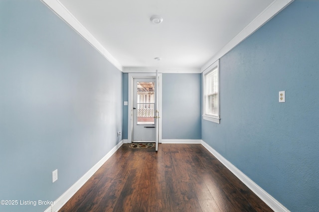 spare room with wood finished floors, ornamental molding, and baseboards