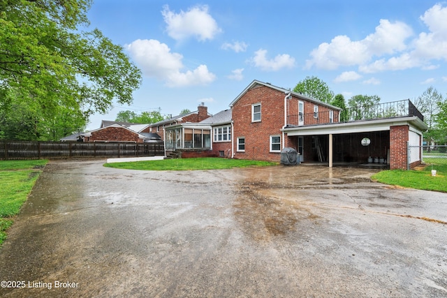 exterior space featuring a chimney, a yard, brick siding, fence private yard, and driveway