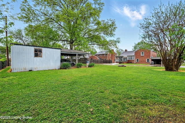 view of yard with fence, a detached carport, and an outdoor structure