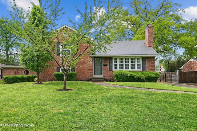 tri-level home with fence, a chimney, brick siding, and a front lawn