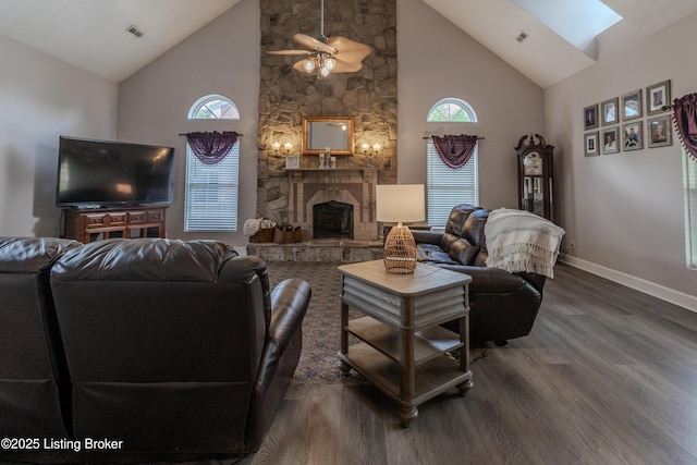living area with a skylight, high vaulted ceiling, ceiling fan, and wood finished floors