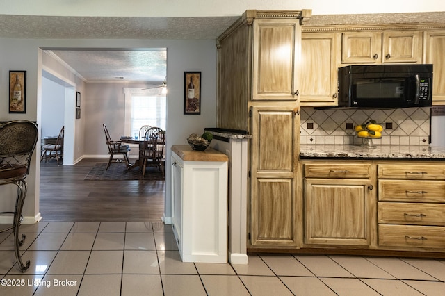 kitchen with light tile patterned flooring, black microwave, backsplash, baseboards, and a textured ceiling