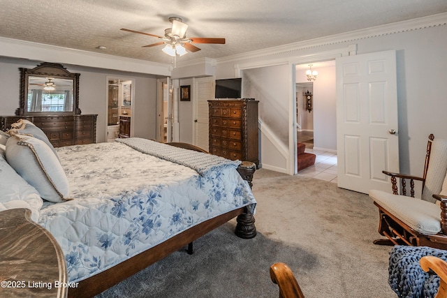 bedroom featuring a closet, crown molding, a ceiling fan, light colored carpet, and ensuite bathroom