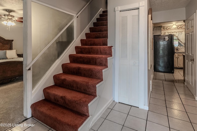 stairway featuring tile patterned floors, a textured ceiling, and ceiling fan