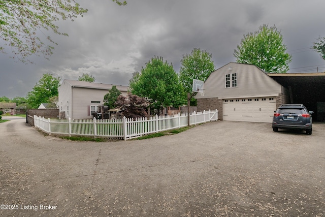 view of property exterior featuring driveway, a gambrel roof, fence private yard, and a garage