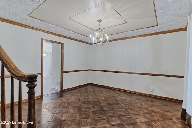 empty room featuring ornamental molding, baseboards, a chandelier, and a tray ceiling