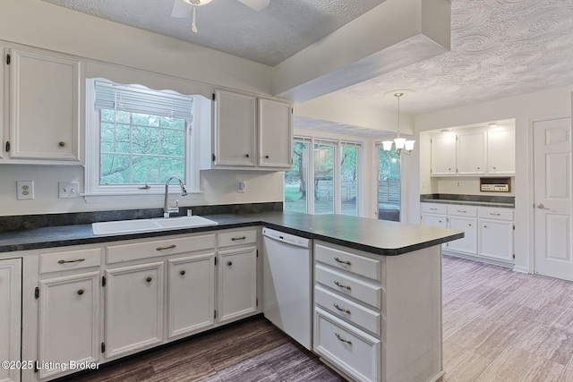 kitchen with white cabinets, a sink, a peninsula, and white dishwasher
