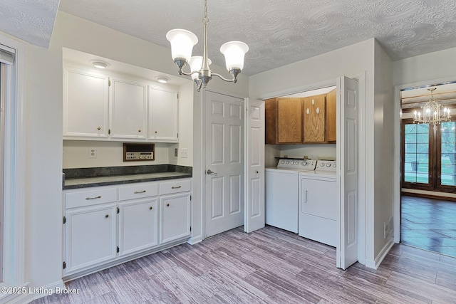 laundry area featuring cabinet space, light wood-style flooring, separate washer and dryer, and a notable chandelier