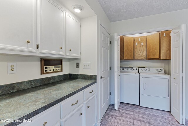 laundry area with washing machine and dryer, light wood finished floors, and cabinet space