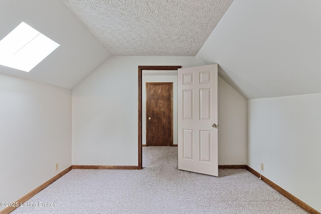 bonus room featuring lofted ceiling with skylight, light colored carpet, and baseboards