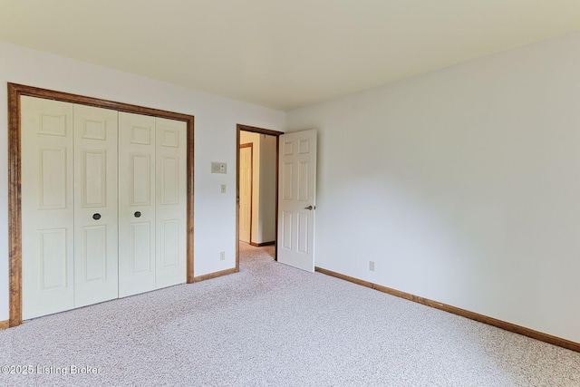 unfurnished bedroom with baseboards, a closet, and carpet flooring
