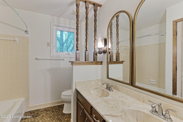full bath featuring toilet, double vanity, a sink, and shower / washtub combination