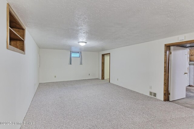 below grade area with a textured ceiling, carpet flooring, and visible vents