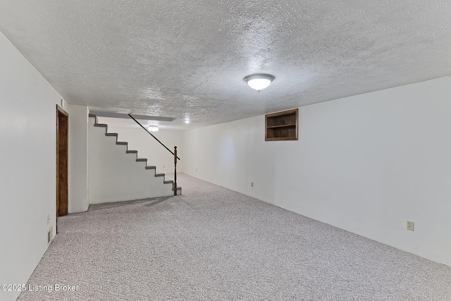finished basement featuring a textured ceiling, carpet flooring, stairway, and visible vents