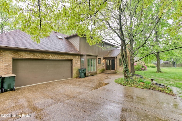 view of front of house with brick siding, roof with shingles, a front yard, concrete driveway, and an attached garage