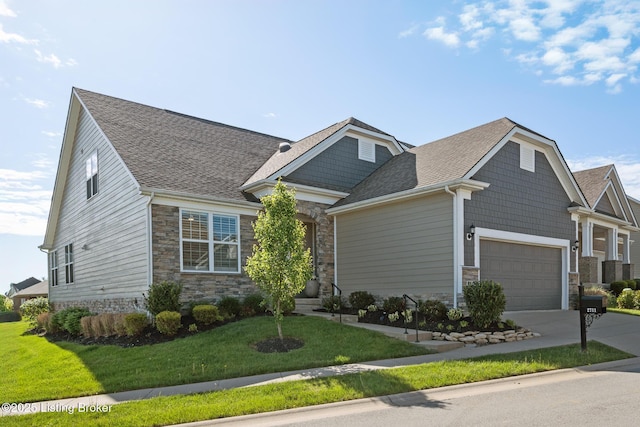 view of front of property with roof with shingles, concrete driveway, a front lawn, and stone siding