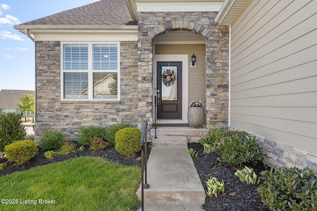 view of exterior entry featuring roof with shingles and stone siding