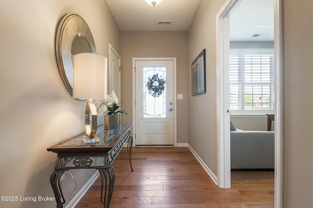 doorway featuring baseboards, visible vents, and hardwood / wood-style flooring