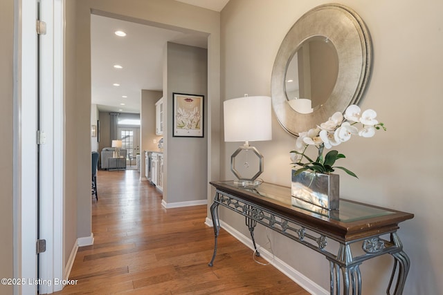 hall featuring baseboards, recessed lighting, and wood finished floors