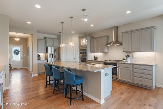 kitchen featuring gray cabinetry, stainless steel appliances, wall chimney exhaust hood, and a sink