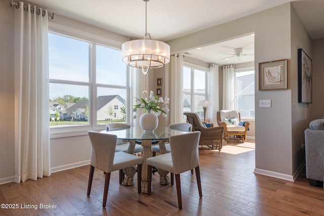 dining space with baseboards, ceiling fan with notable chandelier, and hardwood / wood-style floors