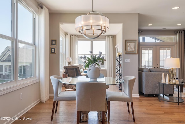 dining area featuring baseboards, a notable chandelier, french doors, and light wood-style floors