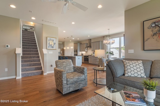 living area featuring visible vents, stairs, baseboards, ceiling fan, and light wood-style flooring