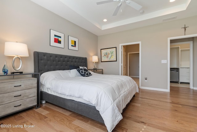 bedroom featuring a tray ceiling, wood finished floors, and visible vents
