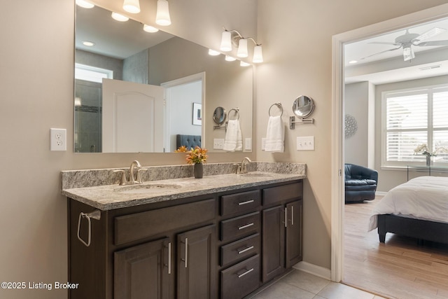 bathroom featuring connected bathroom, double vanity, baseboards, and a sink