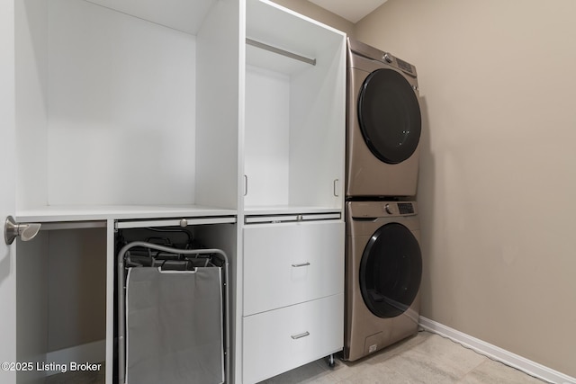 clothes washing area featuring stacked washer and dryer, laundry area, and baseboards