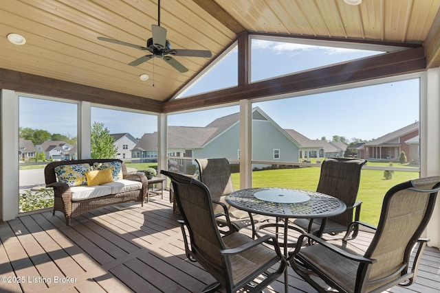 sunroom / solarium with a residential view, a ceiling fan, and beam ceiling